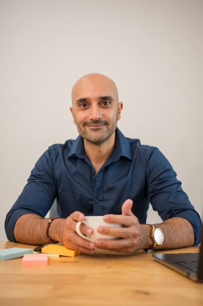 Arash Rahmati sitting at table looking at camera